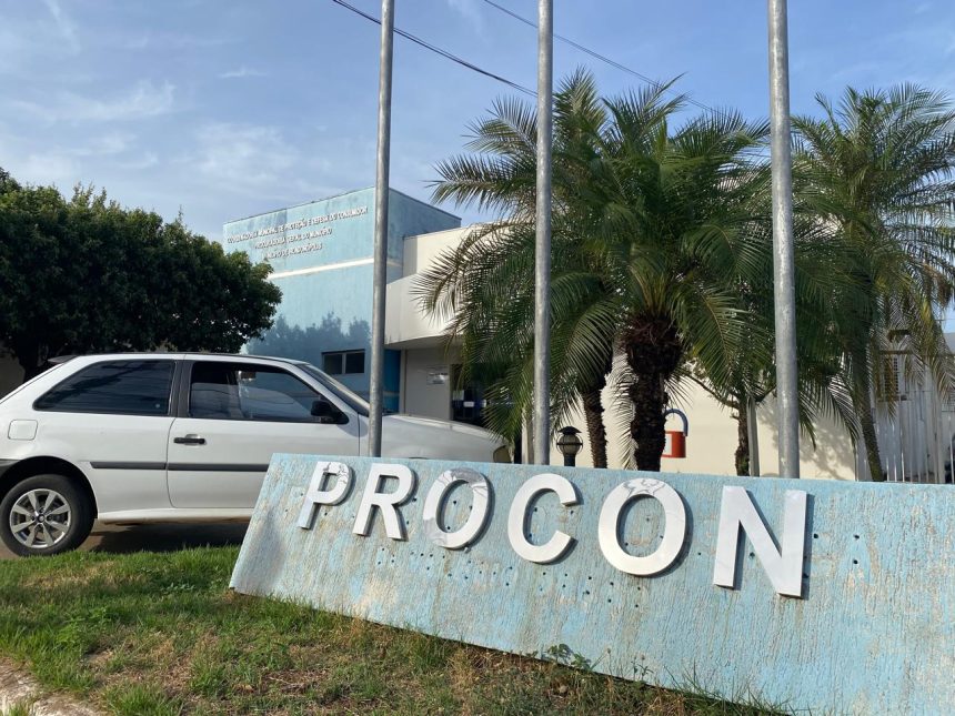 Fiscal do Procon em loja de preço único em Rondonópolis, diante de prateleiras de eletrodomésticos, durante ação que constatou prática de venda casada
