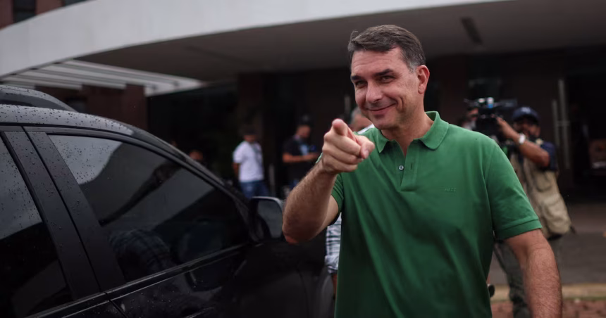 Senador Flávio Bolsonaro em entrevista coletiva, gesticulando enquanto responde sobre a eventual candidatura à Presidência em 2026 e o “preço” para desistir