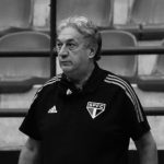 Foto do treinador Cláudio Mortari à beira da quadra orientando sua equipe durante uma partida de basquete.