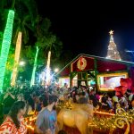 Praça Brasil iluminada com decoração do Natal do Amor, com árvores coloridas, túnel de luzes e famílias reunidas para a abertura do evento