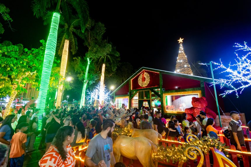 Praça Brasil iluminada com decoração do Natal do Amor, com árvores coloridas, túnel de luzes e famílias reunidas para a abertura do evento