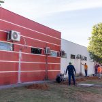 Técnico realizando manutenção em aparelho de ar-condicionado split em ambiente externo.