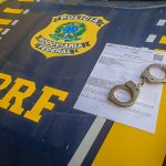 Viatura da Polícia Rodoviária Federal estacionada em rodovia durante abordagem a ônibus.