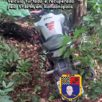 Motocicleta Honda Twister branca recuperada pela Polícia Militar de Rondonópolis às margens de um rio.