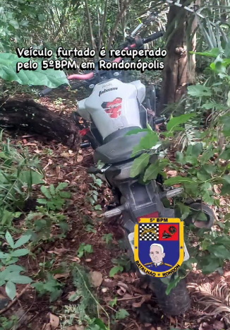 Motocicleta Honda Twister branca recuperada pela Polícia Militar de Rondonópolis às margens de um rio.