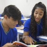 Jovem estudante em frente a um computador acessando o site do Inep para conferir o resultado do Enem.