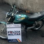 Motocicleta Honda Titan verde estacionada em pátio policial após apreensão por adulteração.