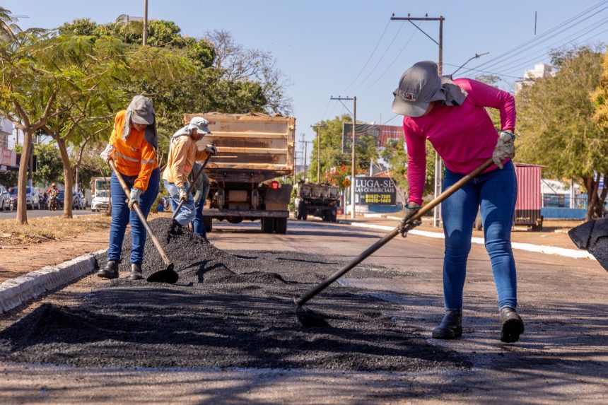 Funcionários da prefeitura realizando aplicação de microrrevestimento asfáltico em avenida de Rondonópolis.