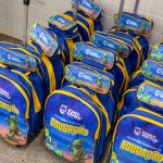 Alunos da rede municipal de Rondonópolis segurando novas mochilas e materiais escolares.