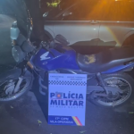 Motocicleta azul modelo CG Fan 125 estacionada sob fiscalização da Polícia Militar de Mato Grosso.