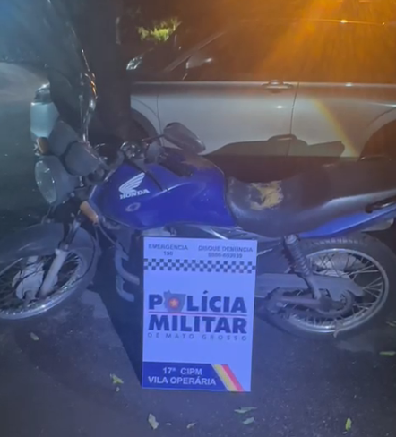 Motocicleta azul modelo CG Fan 125 estacionada sob fiscalização da Polícia Militar de Mato Grosso.