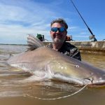 Pescador praticando a modalidade pesque e solte em um rio de Mato Grosso durante o pôr do sol.