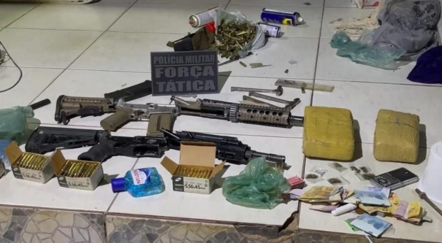 Arsenal com fuzis, revólveres e tabletes de maconha dispostos sobre uma mesa após operação policial.